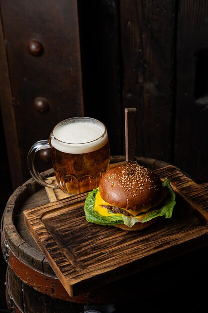 A glass of beer and a burger on a wooden table