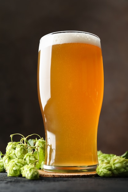 Glass of beer and hop cones on wooden table