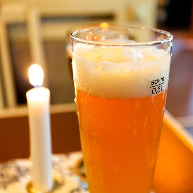 Glass of beer and lit candle on table