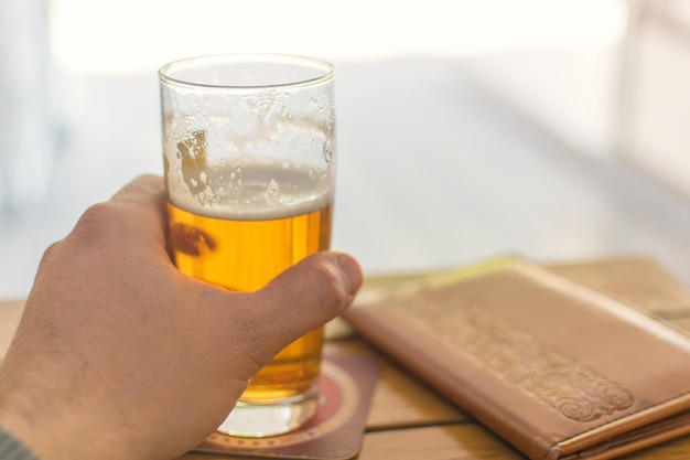 A glass of beer in a man's hand on the table of a street cafe