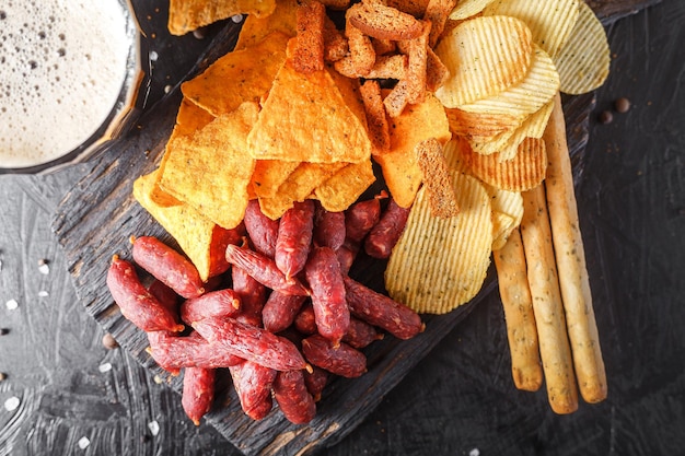 Foto bicchiere di birra mini salsicce grissini e cracker con salami affumicati bastoncini di legno vintage