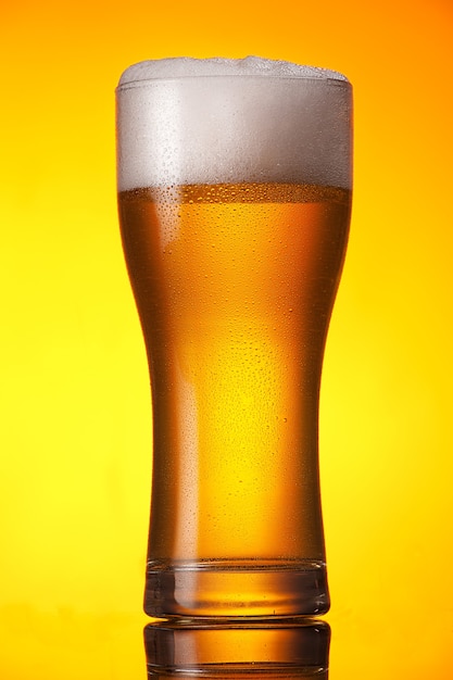 Glass of beer over orange background