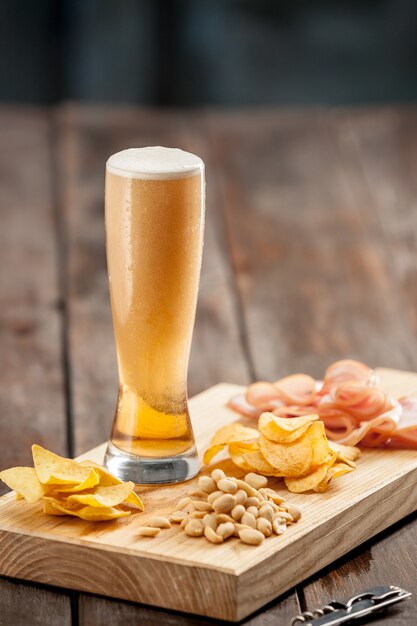 The glass of Beer and potato chips, pistachios isolated on a white