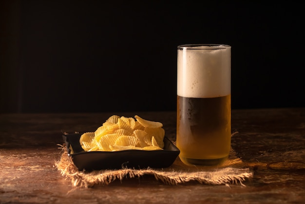 Foto bicchiere di birra e patatine su un tavolo di legno