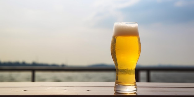 A glass of beer on a table with a view of the ocean in the background