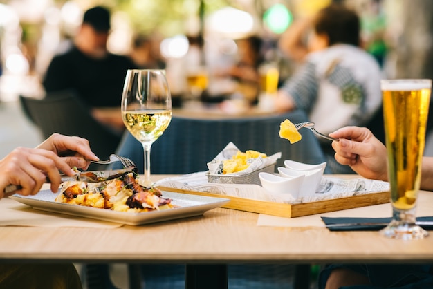 A glass of beer and wine on a table with dishes two girls have lunch together in a restaurant on the terrace