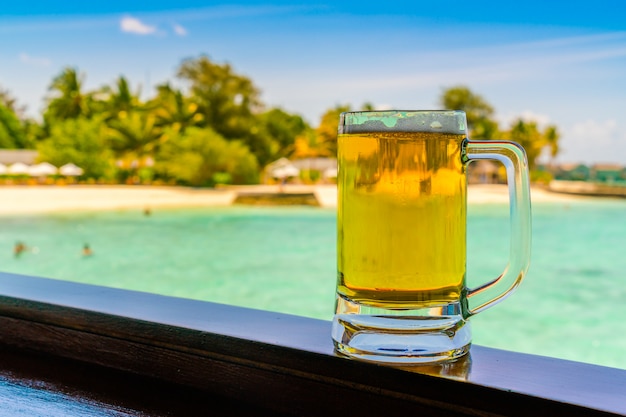 A glass of beer with Beautiful tropical Maldives island .