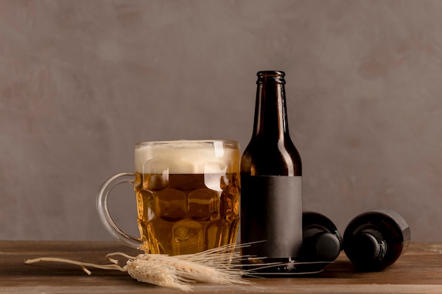 Glass of beer with foam and brown bottles of beer on wooden table