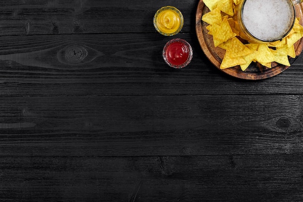 Glass of beer with nachos chips on a wooden background. Top view. Copy space. Still life. Flat lay