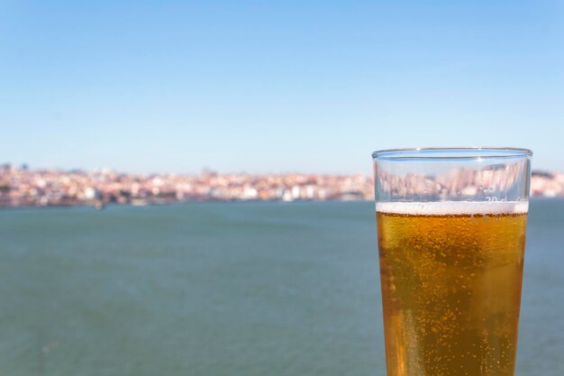 Glass of beer with sea and city in the background