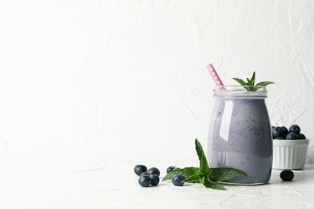 Glass of berry milkshake on white table