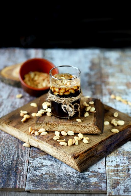 A glass of black soda drink and peanuts. Salted peanuts in a glass with coke. American food.