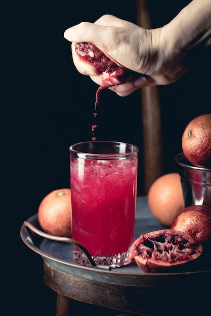 Glass of blood orange juice with ice and orange fruits on dark background