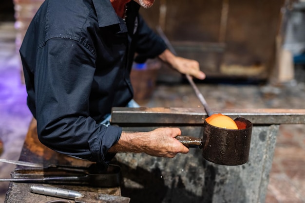 Glass blower at work in workshop in Murano Italy making handmade glassware