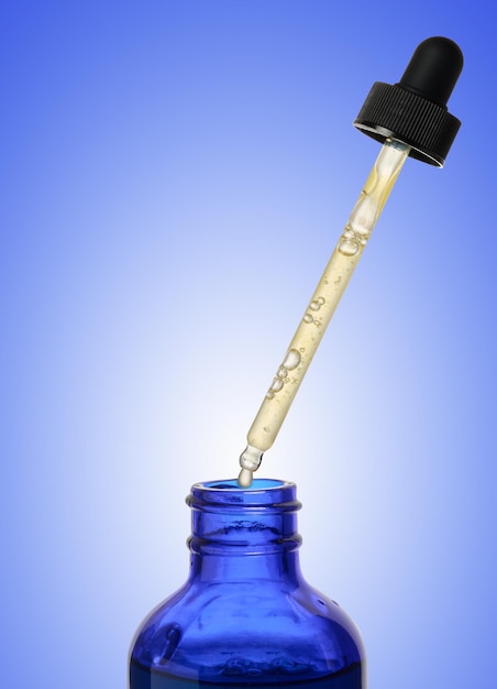 파란색 배경 에 드로퍼 가 있는 유리 파란색 병, 화장품 을 담은 용기