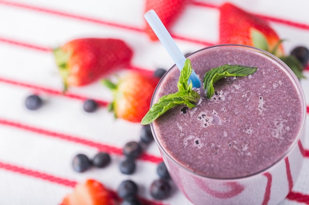 Glass of blueberry smoothie on  background