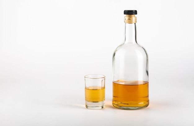 Glass and bottle of alcohol on a white backgroundConcept of alcoholism