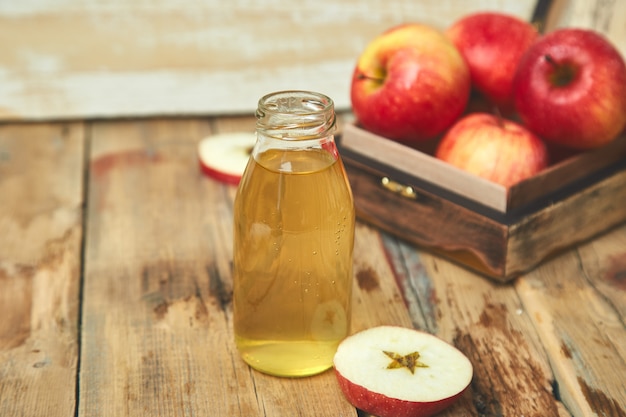 Photo glass bottle of apple organic vinegar and red apples