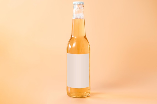 Photo a glass bottle of beer with a white blank label on an orange background cool golden drunk fluid gold brewed alcoholic refreshing pub chill brand product bottle