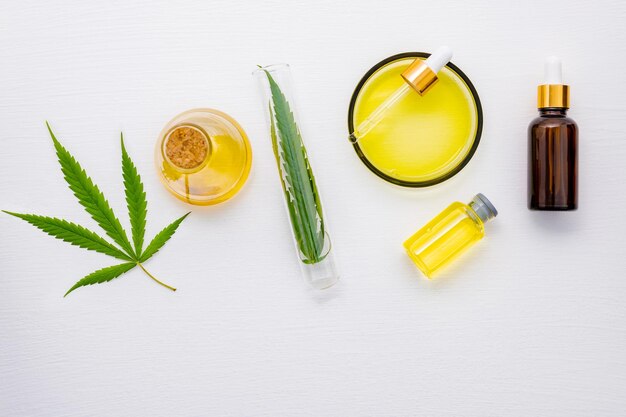Glass bottle of cannabis oil and hemp leaves set up on white background
