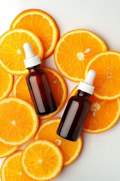 Glass bottle of essential citrus oil on oranges background