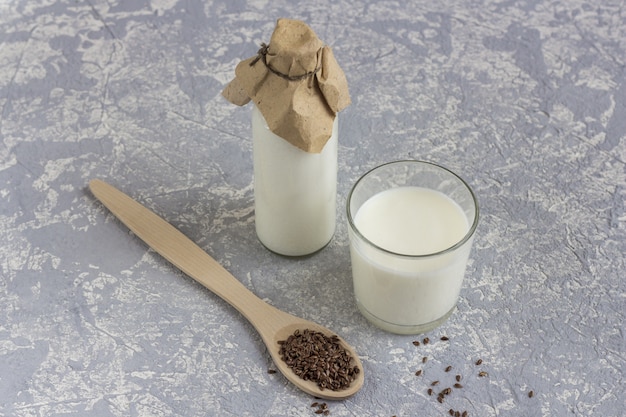 Glass bottle and glass of yogurt with flax seeds, wooden spoon with flax seeds