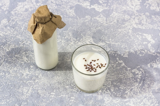 Glass bottle and glass of yogurt with flax seeds.