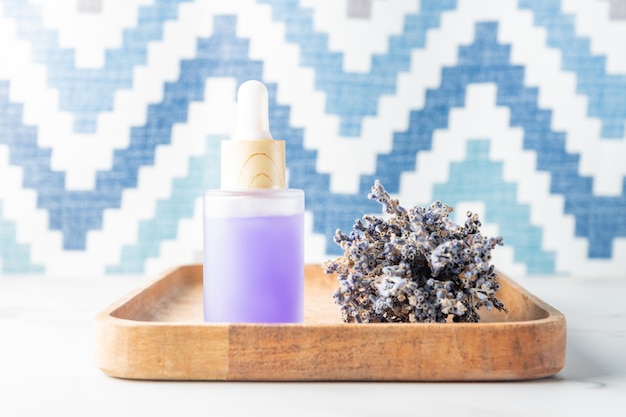 Bottiglia di vetro di olio essenziale di lavanda con fiori di lavanda secchi su vassoio rustico in legno aromaterapia spa massaggio concetto lavendula oleum