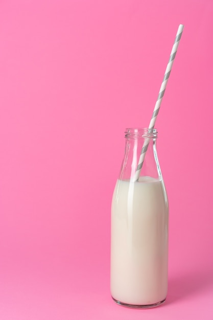 glass bottle of milk against pink background