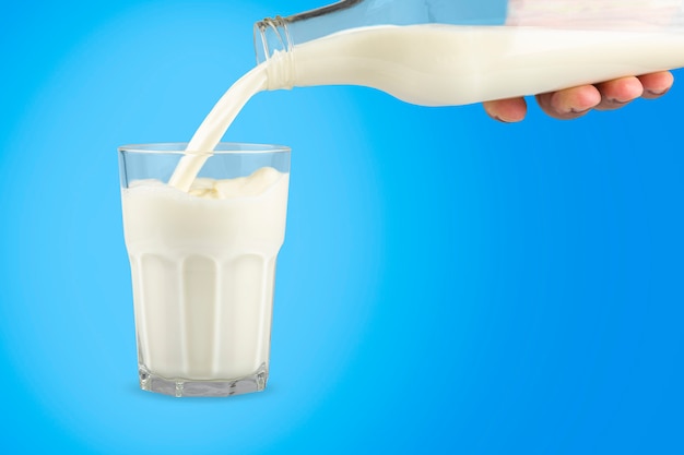 Glass and bottle of milk on blue background