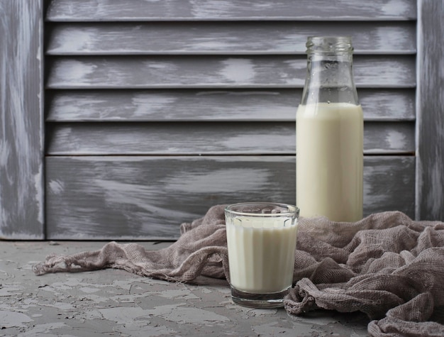 Glass and bottle  of milk on gray concrete background. Selective focus