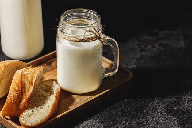 glass bottle of milk with sliced baguette bread