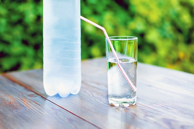 A glass and a bottle of mineral water on the table in the garden