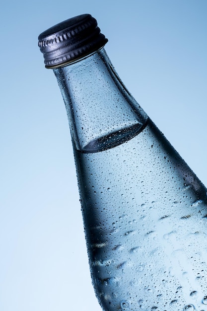 Фото Стеклянная бутылка воды с каплями росы