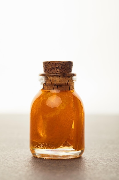 Glass bottle of organic essential oil with cut fruit isolated on white