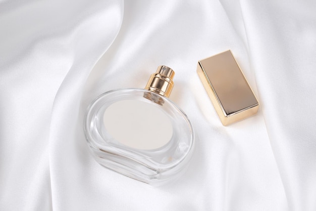 Glass bottle of perfume on a white silk the concept of expensive perfume and cosmetics