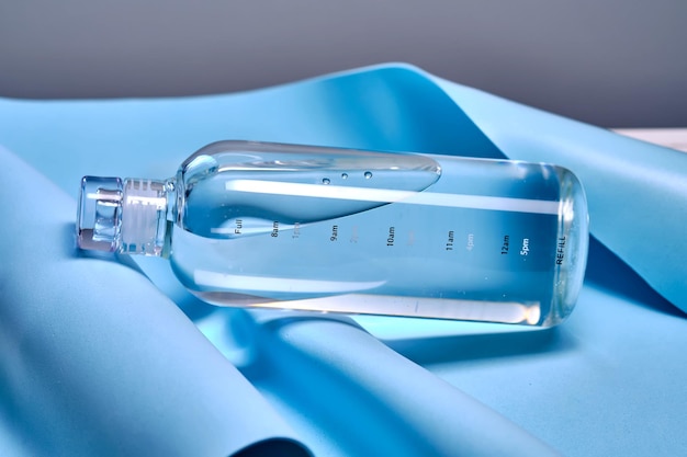 A glass bottle of pure water against the background of blue waves