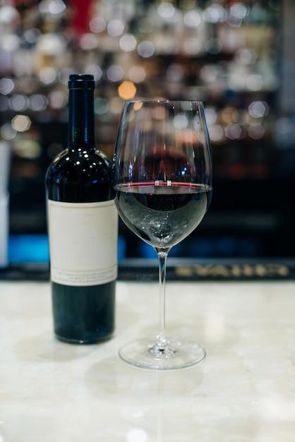 Glass and bottle of red wine on bar counter