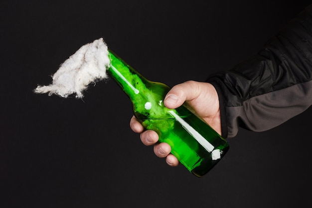 Glass bottle, the so-called Molotov cocktail in the hand of the activist. Isolated on a black background.