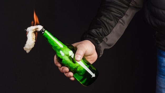 Glass bottle the socalled Molotov cocktail in the hand of the activist Isolated on a black background