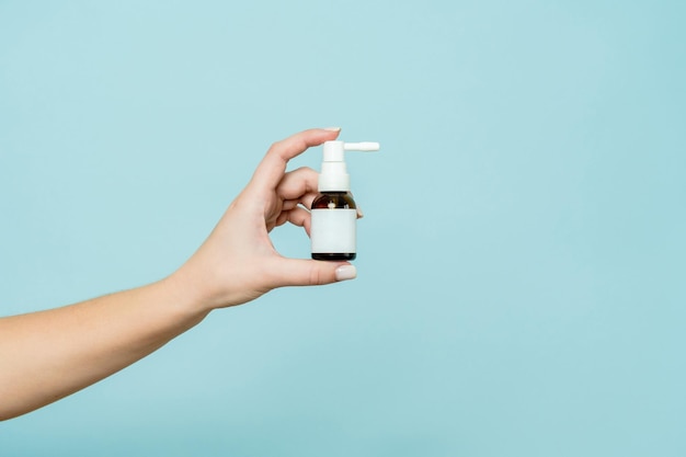 Glass bottle spray in hand on blue background