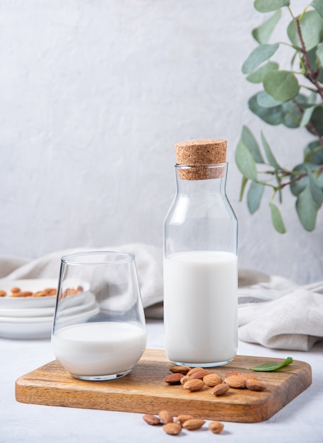 A glass and bottle of  vegan almond milk and a few  nuts on a white  background