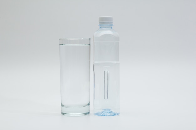 glass and bottle of water on white background