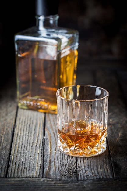 Photo glass and a bottle of whiskey on dark wooden table