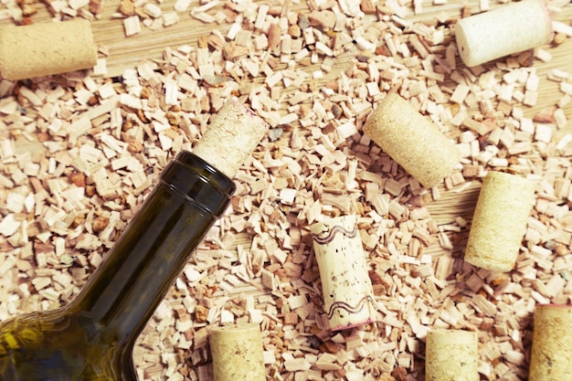 Glass bottle of wine with corks On wooden background with scattered sawdust