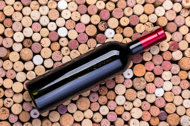 Glass bottle of wine with corks on wooden table