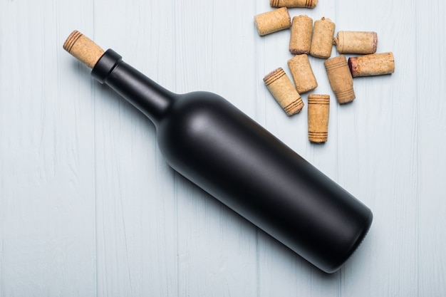 Glass bottle of wine with corks on wooden table