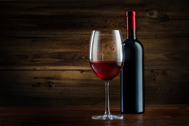 Glass and bottle of wine on a wooden background