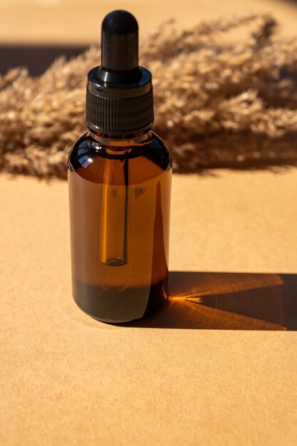 glass bottle with aromatic oil or serum on a brown background. Natural Organic Spa Cosmetic concept