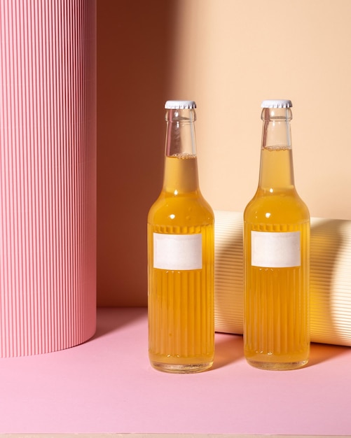 Glass bottle with blank label ice cubes and liquid similar to lemonade beer on pink background